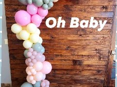 Pastel balloon garland running up a rustic wooden backdrop